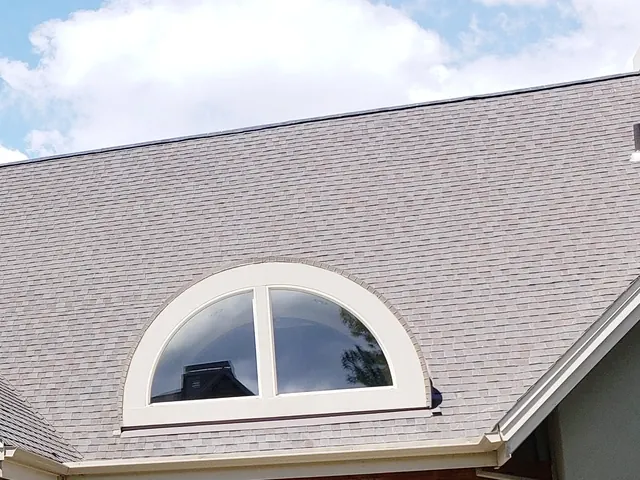The steep shingled roof and arched dormer window of the practice building on NW York Drive.